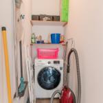 Washing machine, vacuum cleaner, and cleaning supplies in a narrow room.