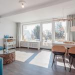 Living and dining area with blue sofa, glass table, and view of balcony.