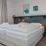 Bedroom with double bed, wall art, and wooden stool.