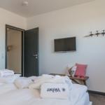 Bedroom with bed, TV, and coat hooks on the wall.