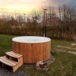 Hochwertiger Whirlpool mit Holzverkleidung und Außentürme im Garten.