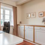 Arbeitszimmer mit Schreibtisch, Stuhl und Fenster mit Vorhängen.