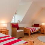 Zimmer mit zwei Betten, Stuhl und Fenstern im Dachgeschoss.
