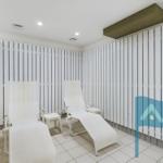 Two white lounge chairs in a room with white vertical panels on the walls.