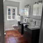 Badezimmer mit zwei Waschbecken, Toilette und Fenster mit Blick nach draußen.