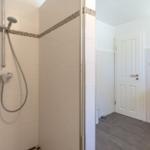 Dusche mit Duschbrause, Waschbecken und Spiegel