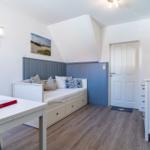 Schlafzimmer mit Bett, Tisch und Schrank. Wandgestaltung in Blau und Weiß.