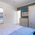Schlafzimmer mit Bett, Kleiderschrank und Schminktisch. Tür führt zu einem weiteren Raum.