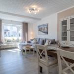 Wohn- und Essbereich mit Sofa, Esstisch und Glaswand-Schrank.