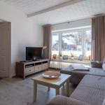 Wohnzimmer mit Sofa, TV und Fenster mit Blick nach draußen.