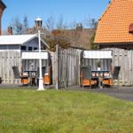Hinterhof mit Grillplatz, Sitzgelegenheiten und Holzzaun. Grasfläche und Terrassenbereich.