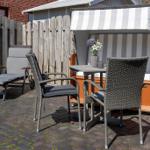 Terrasse mit Liegestuhl, zwei Stühlen und Tisch neben Strandkorb.