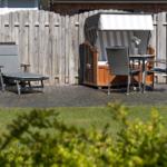 Garten mit Liegestuhl, Hängesessel und Tisch mit Stühlen auf gepflastertem Boden.