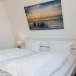 Schlafzimmer mit Doppelbett, Wandbild und Nachttischen mit Lampen.