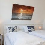 Schlafzimmer mit Doppelbett, Wandbild und Nachttisch mit Lampe.