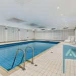 Innenpool mit Liegen und Metalltreppe. Weiße Wände und Bodenfliesen.