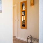 Eingangsbereich mit Spiegel, Wandbeleuchtung und Bild an der Wand.