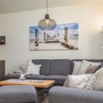 Ein Wohnzimmer mit grauem Sofa, Holztisch und Wandbild an der Wand.