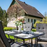 Terrasse mit Tisch und Stühlen vor einem Haus mit Garten.