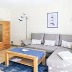 Ein Wohnzimmer mit grauem Sofa, Holztisch und Glasvitrine.