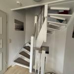 Haus mit Treppe zur oberen Etage. Holzstufen und weiße Geländer.