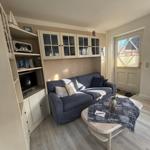 Wohnzimmer mit Sofa, Couchtisch und eingebautem Schrank. Fenster mit Jalousie.