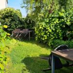 Garten mit grünem Rasen, Bäumen und zwei Holztischen mit Stühlen.
