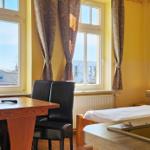 Zimmer mit Bett, Tisch, Stühlen und Fenstern. Blick auf die Straße.