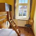 Zimmer mit Holzbett, Fenster und Stuhl.