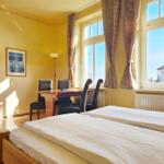 Zimmer mit Doppelbett, Tisch, Stühlen und Fenster mit Blick nach außen.