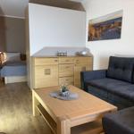 Wohnbereich mit Sofa, Couchtisch und Schlafzimmer im Hintergrund.