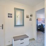 Eingangsbereich mit Spiegelschrank, Sitzbank und Blick ins Wohnzimmer.