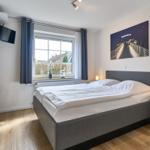 Schlafzimmer mit Doppelbett, Fenster, Nachttisch und Wandbild.