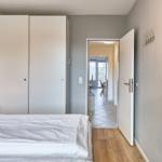 Schlafzimmer mit Bett, Kleiderschrank und Tür zum Flur.
