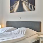 Doppelbett mit weißen Kissen und Bettwäsche, zwei Nachttische mit Lampen, Wandbild über dem Kopfteil.