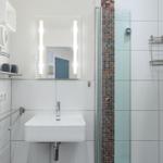 Badezimmer mit Dusche, Waschbecken und Spiegel