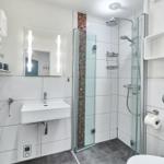 Badezimmer mit Dusche, Waschbecken und Heizkörper
