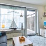 Wohnzimmer mit Sofa, Fernseher und Fenster zur Terrasse.