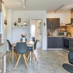 Küche mit Essbereich und Sitzgelegenheit. Holztisch, graue Stühle und moderne Einrichtung.