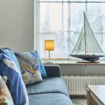 Ein Sofa mit Kissen vor einem Fenster mit Segelboot und Leuchtturmmodell.