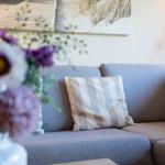 Ein grauer Sofa mit Kissen und Blumen im Vordergrund.