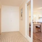 Flur mit Garderobe und Tür zur Wohnküche mit Sofa und Esstisch.
