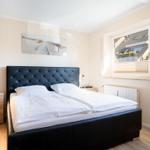 Schlafzimmer mit Doppelbett, Nachttischen und Fensterblick.