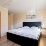 Schlafzimmer mit Doppelbett, Nachttischen und Blick in das Badezimmer.