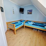 Zwei Einzelbetten mit blauer Bettwäsche, Holzboden und schräger Decke.