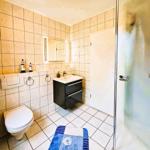 Bathroom with shower, sink and toilet. Tiled walls and floor.