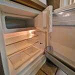 Empty refrigerator with open door and visible shelves.