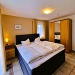 Bedroom with double bed, wooden wardrobe, and nightstand with lamp.