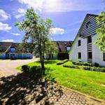 House with green lawn and paved path under blue sky.