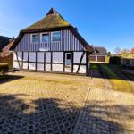 Holiday home with half-timbered structure and thatched roof. Garden with paved path.